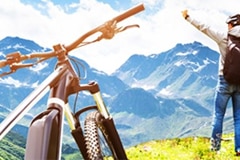 ebike in the foreground with a man standing at the edge of a rise in the middle ground and mountains stretching off in the background