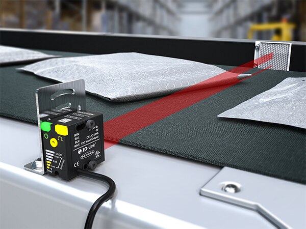 Image of Banner Engineering wide-beam sensor detecting thin mailers with 25 mm beam coverage