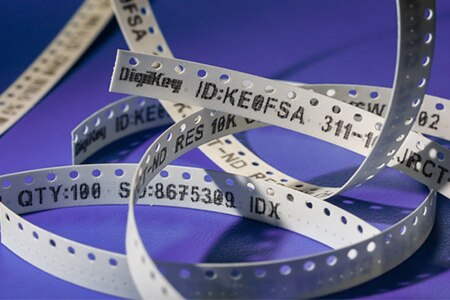 A strip of part tape with text with tracking and manufacture information printed on one side