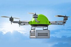Green quadcopter drone against blue sky