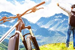 ebike in the foreground with a man standing at the edge of a rise in the middle ground and mountains stretching off in the background